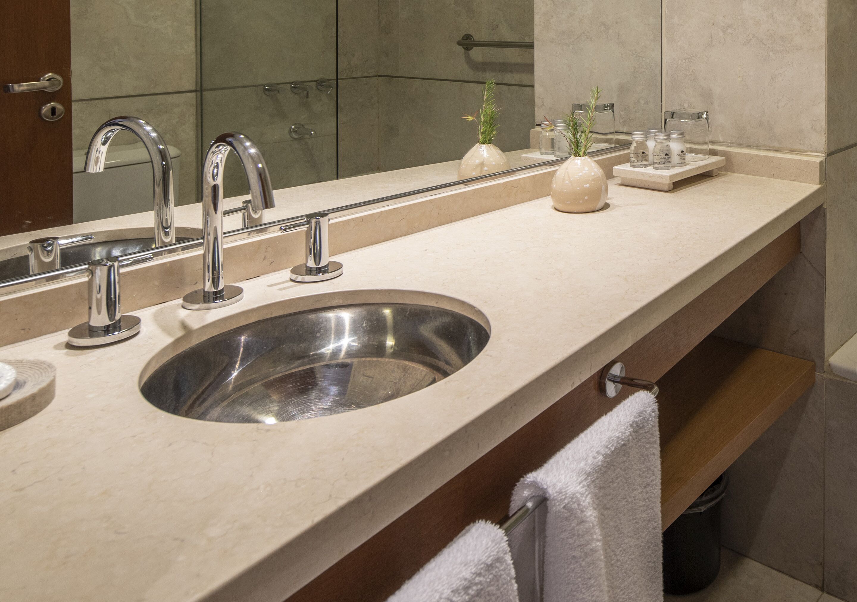 A modern bathroom with a large sink, two faucets, and a mirror.