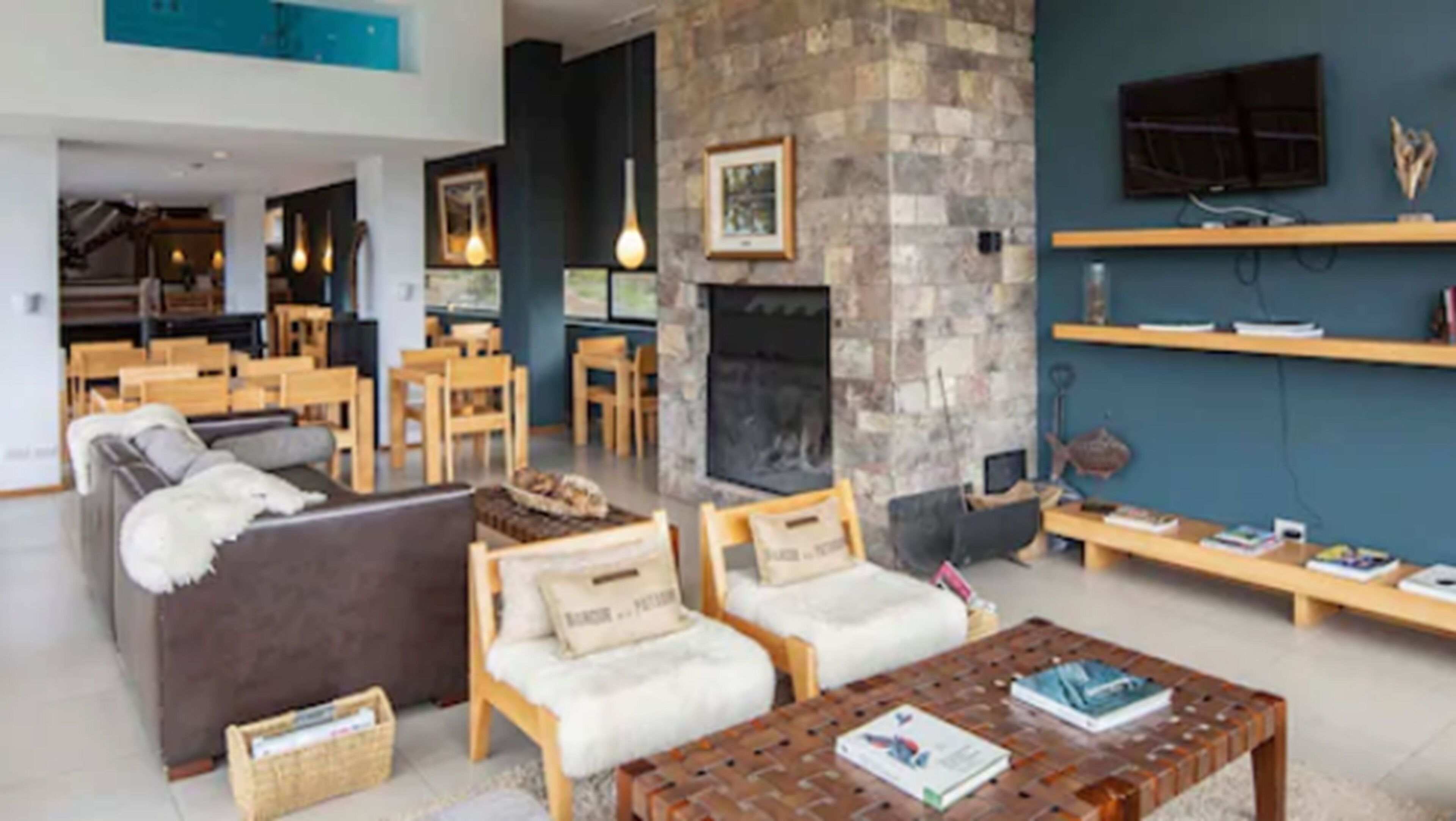 A spacious living area with a fireplace, wooden furniture, and a television mounted on the wall.