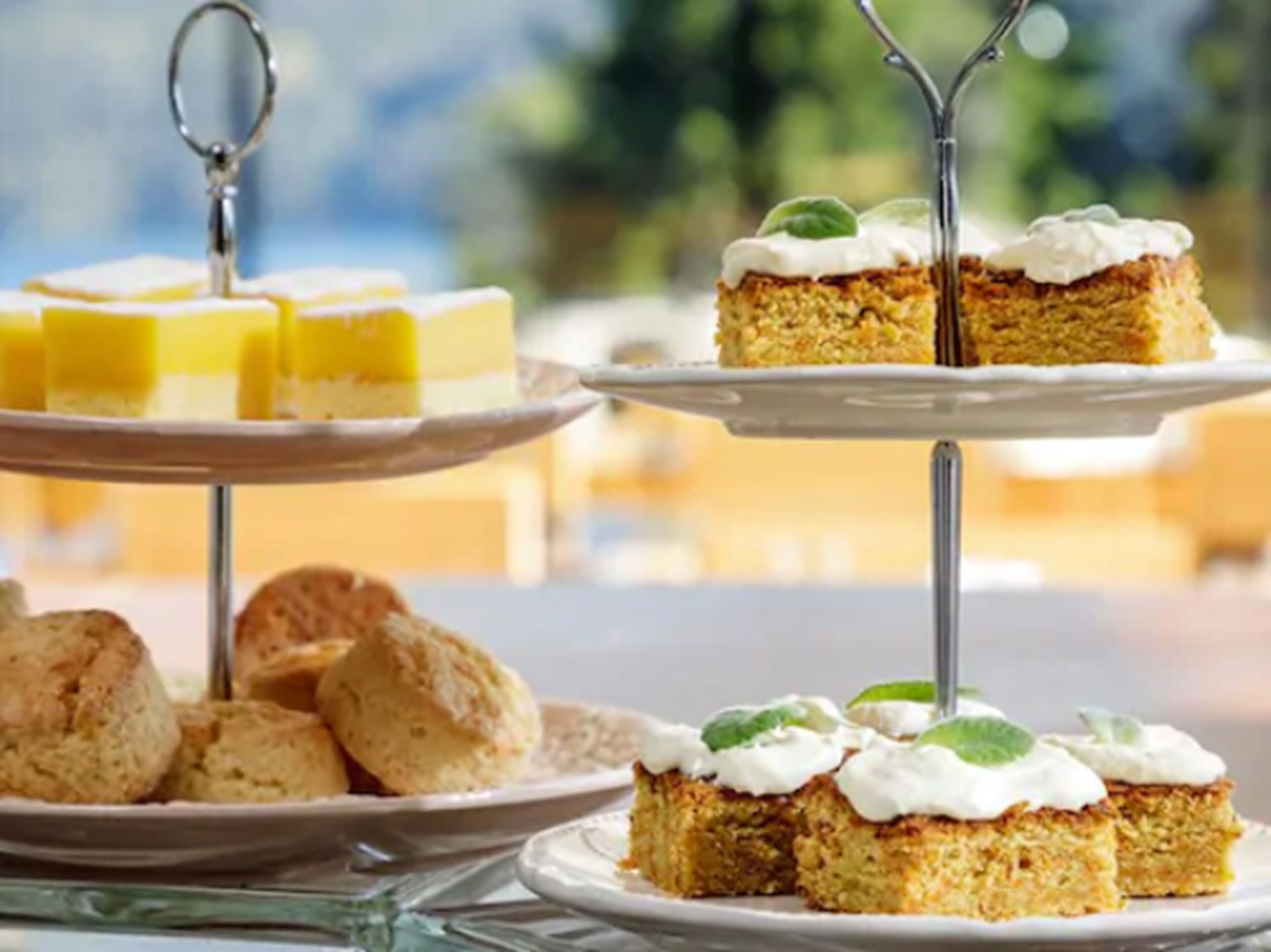 A dessert display with cakes and scones on stands.
