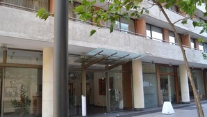 Un edificio moderno con entrada de vidrio, ventanas amplias y una escalera visible que conduce a un nivel superior.