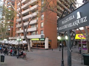 Une place sur laquelle on peut lire l’inscription « Plaza de Diego de Velázquez », entourée de bâtiments et agrémentée d’espaces de repos en plein air.