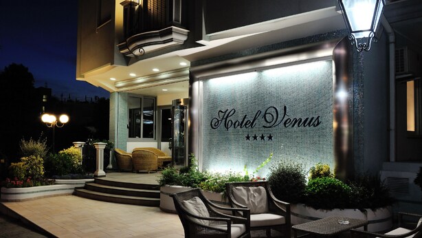 A hotel entrance with a sign reading "Hotel Venus" and a staircase leading to the entrance. There are wicker chairs and a table outside. - Hotel Venus (Gabicce Mare)