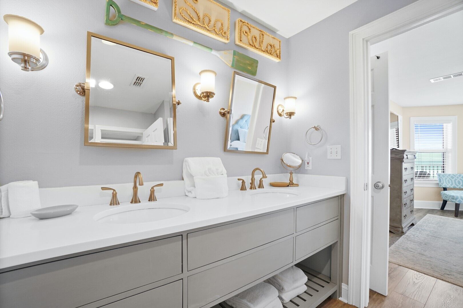 Un baño moderno con lavamanos doble, accesorios dorados y varios espejos.