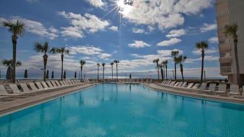 Relax by the ocean-view pool surrounded by palm trees and lounge chairs.
