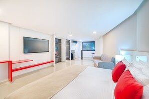A modern hotel room with a large bed, a TV mounted on the wall, a seating area with a red bench, and a closet with a mirror. - Hotel Blue 66 (Cali)