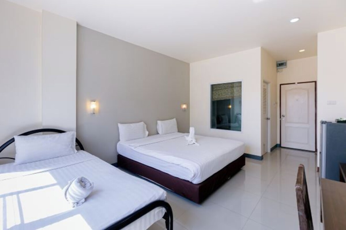 A hotel room with two beds, a desk, and a door leading to another room.