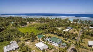 An aerial view of a residential area with houses, a swimming pool, and a beach. - Whitehouse Apartments Rarotonga (Rarotonga)