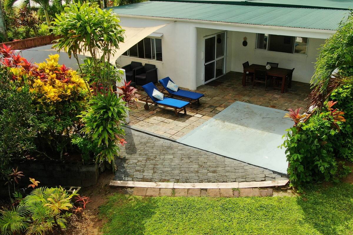 A house with a patio area, outdoor furniture, and lush greenery.