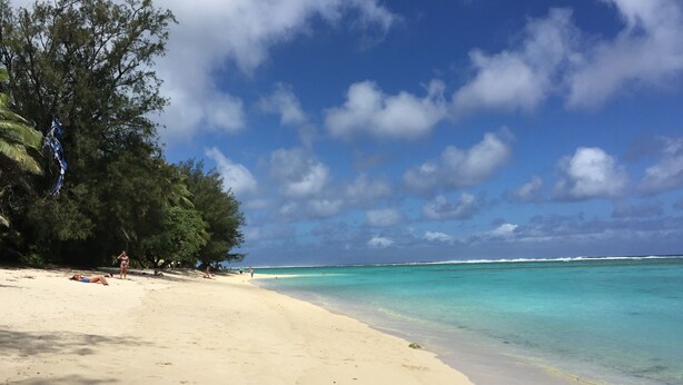 A beach with clear turquoise water, a sandy shore, and some trees. - Whitehouse Apartments Rarotonga (Rarotonga)