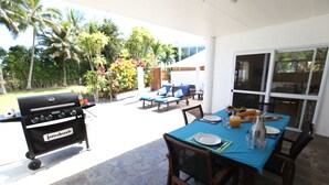 An outdoor patio with a table set for dining, a grill, and lounge chairs. - Whitehouse Apartments Rarotonga (Rarotonga)