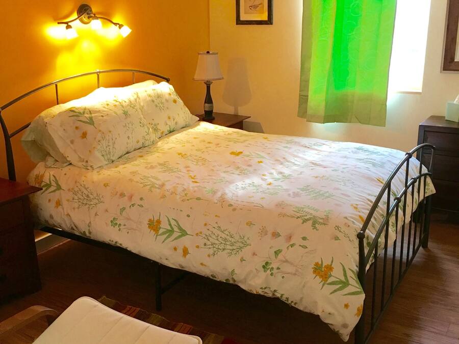 A neatly made bed with floral bedding, a bedside lamp, and a framed picture on the wall.