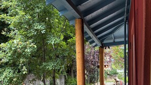 Un espacio al aire libre cubierto con pilares de madera, un sendero de grava y follaje circundante.