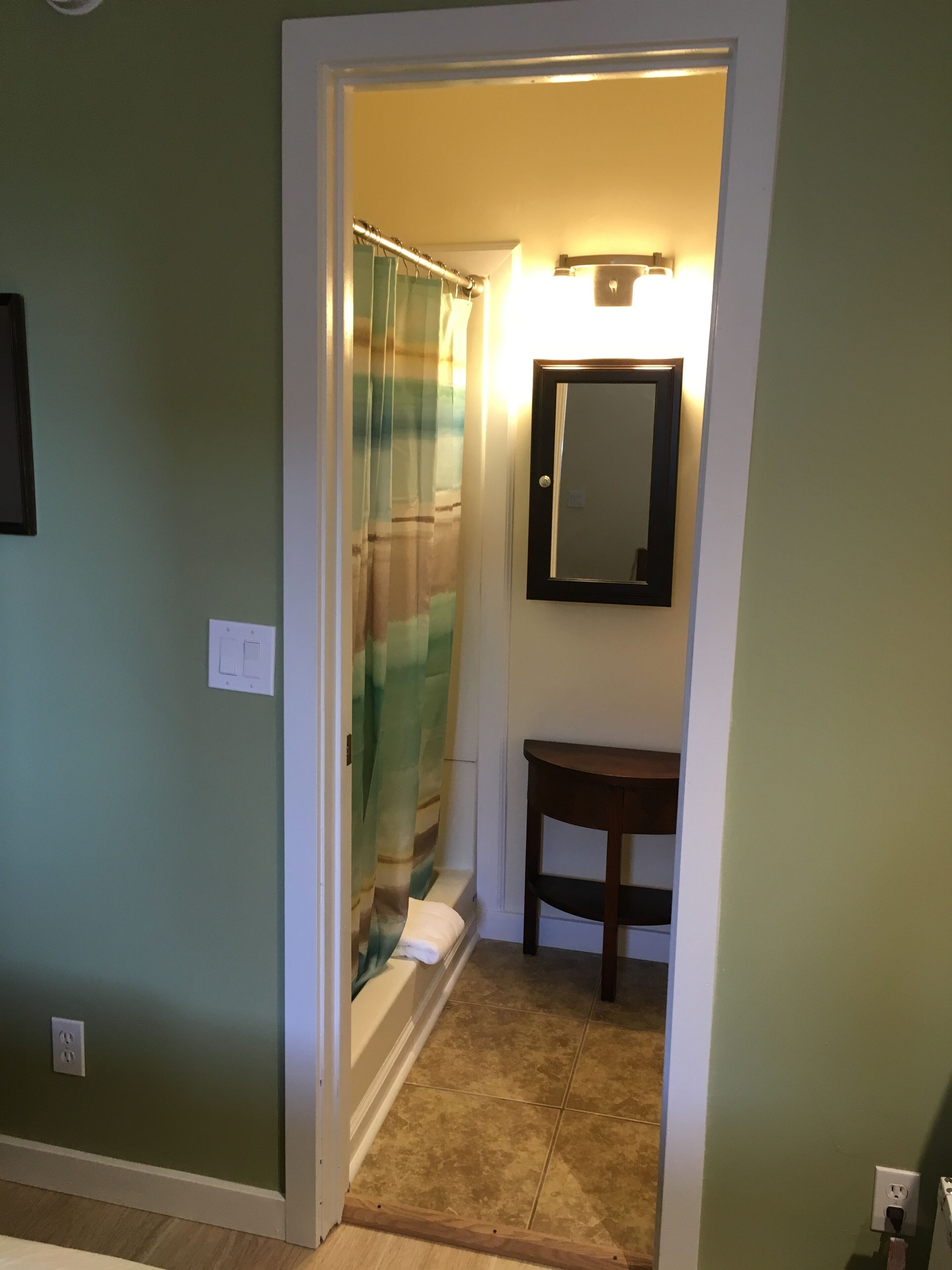 A bathroom with a shower curtain, a mirror, and a small sink.