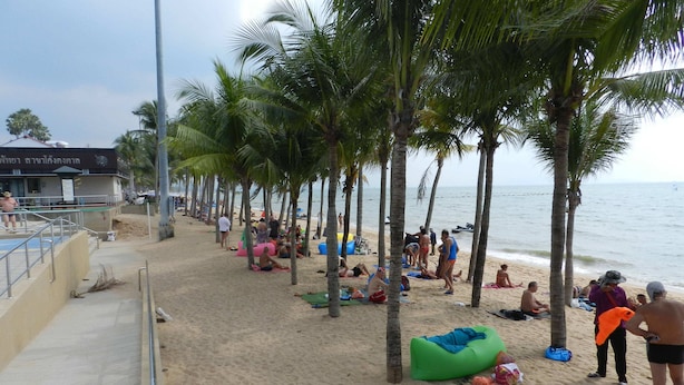 A beach with palm trees, people sunbathing, and a lifeguard tower. - Apartments Alex Group NEOcondo Pattaya (Pattaya)