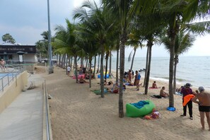 A beach with palm trees, people sunbathing, and a lifeguard tower.