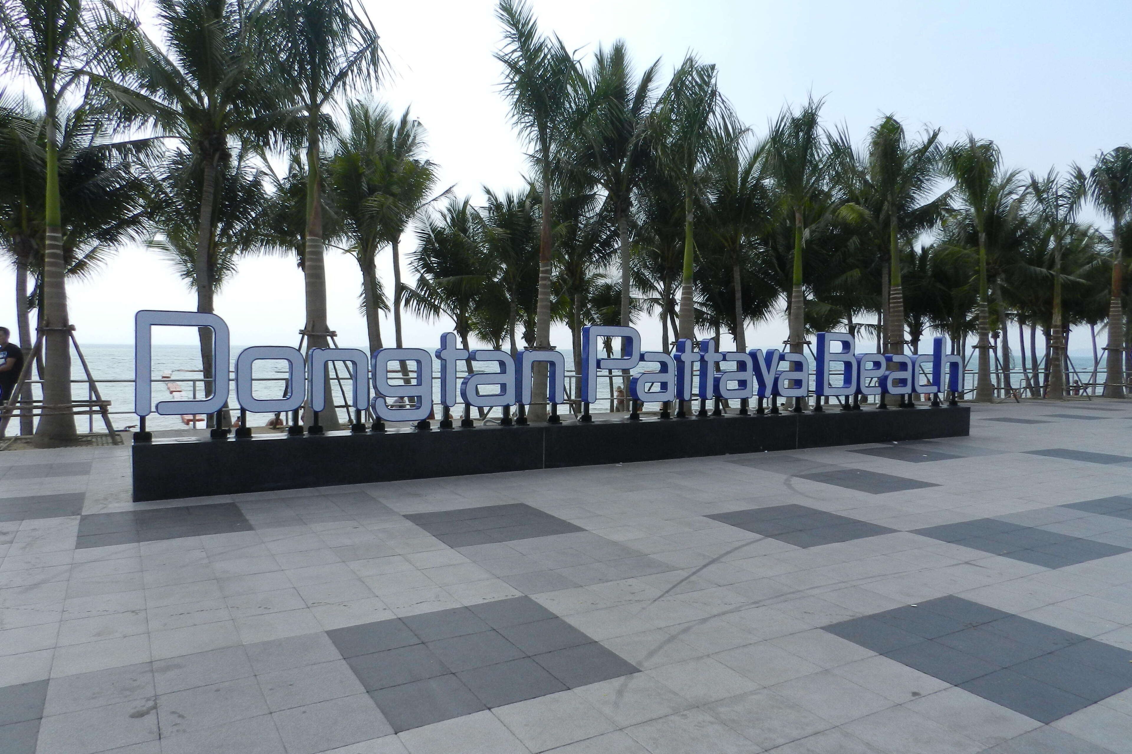 A sign with the text "Dongfan Paradise Beach" in a public area with palm trees and a tiled floor.
