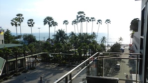 A balcony with a view of a street lined with palm trees and a body of water in the distance. - Apartments Alex Group NEOcondo Pattaya (Pattaya)