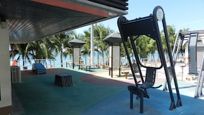 An outdoor seating area with a covered section, exercise equipment, and a view of the beach. - Apartments Alex Group NEOcondo Pattaya (Pattaya)