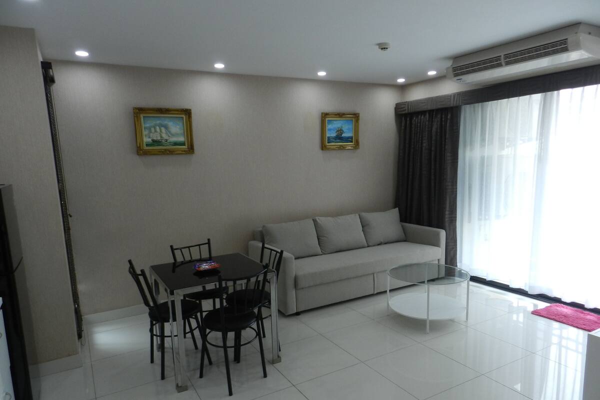 Una sala de estar moderna con comedor, un sofá y dos cuadros en la pared.