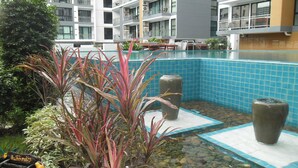 A modern hotel with a rooftop pool area featuring blue-tiled flooring, potted plants, and a view of the building's balconies. - Apartments Alex Group NEOcondo Pattaya (Pattaya)