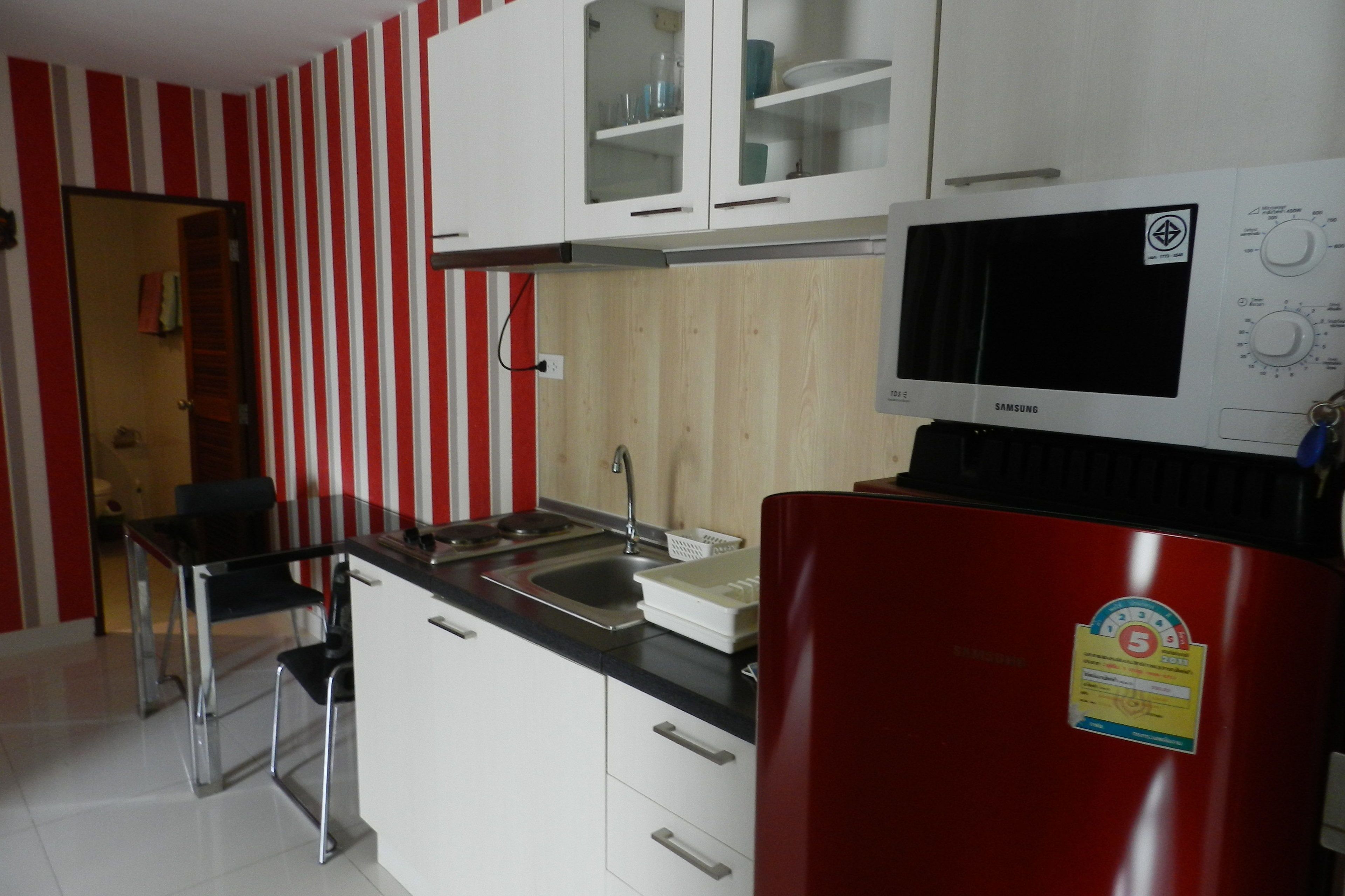 A kitchen with white cabinets, a red refrigerator, and a microwave.