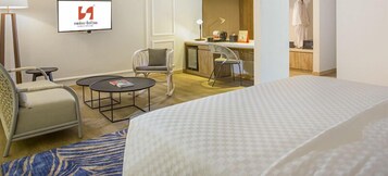 Una habitación de hotel con una cama, dos sillas, una mesita redonda, un escritorio y una televisión.