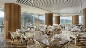 Un comedor amplio con techos altos, ventanas grandes que ofrecen vistas al exterior y muebles blancos modernos.
