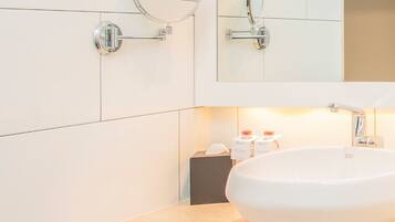 Une salle de bain moderne avec un grand lavabo ovale, un miroir rond et un robinet chromé.