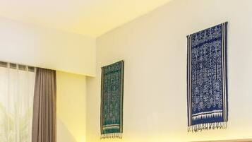 A hotel room with two beds, a window with curtains, and two wall hangings.