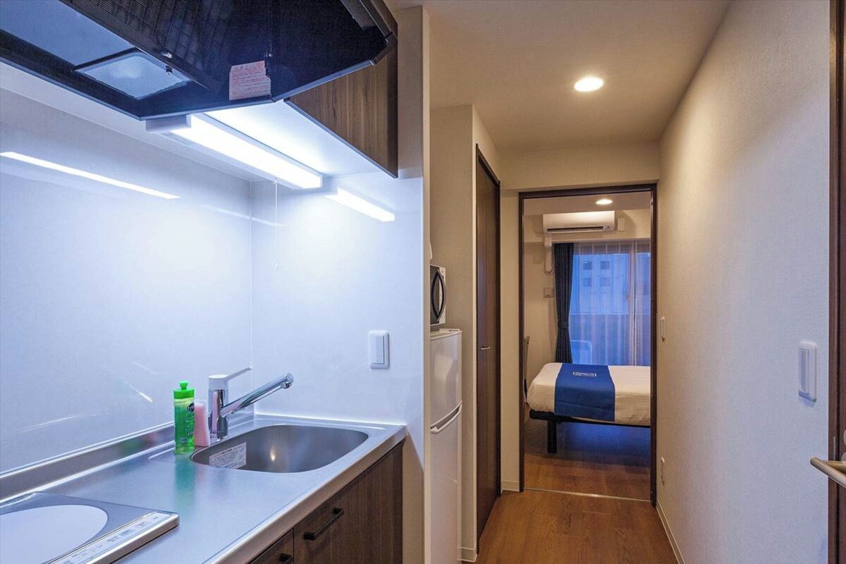 Una kitchenette compacta con pileta, grifo y microondas.
