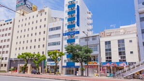 A multi-story hotel with a blue and white facade, several balconies, and a visible entrance.