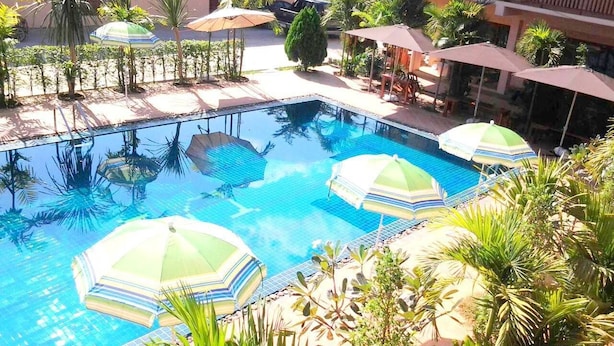 A pool area with multiple umbrellas and palm trees.