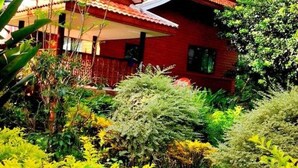 A red building with a white roof, surrounded by lush greenery.