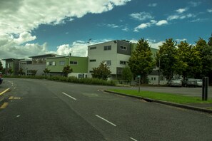 A street view with modern multi-story buildings, a clear sky, and parked cars. - Te Henui Lodge (New Plymouth)