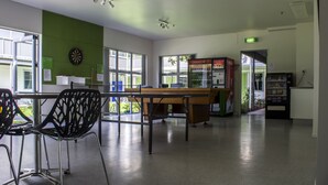 A spacious room with a long table, chairs, a dartboard, and a vending machine. - Te Henui Lodge (New Plymouth)