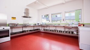 A kitchen with stainless steel appliances, a red floor, and a warning sign on the wall. - Te Henui Lodge (New Plymouth)