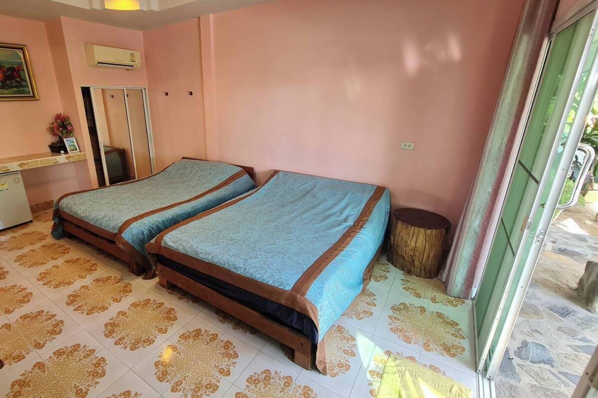 Une chambre avec deux lits, un petit bureau, un miroir et une porte.