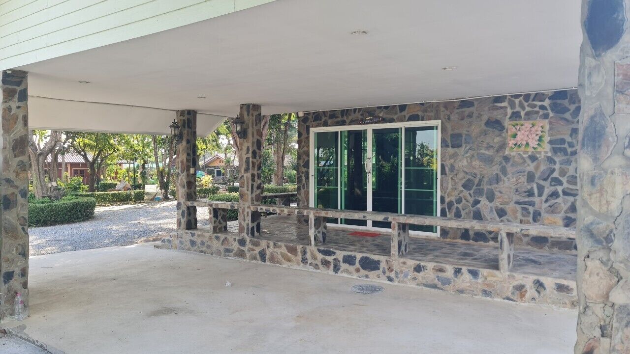 Un espacio al aire libre techado con paredes de piedra y una entrada de puerta de cristal.