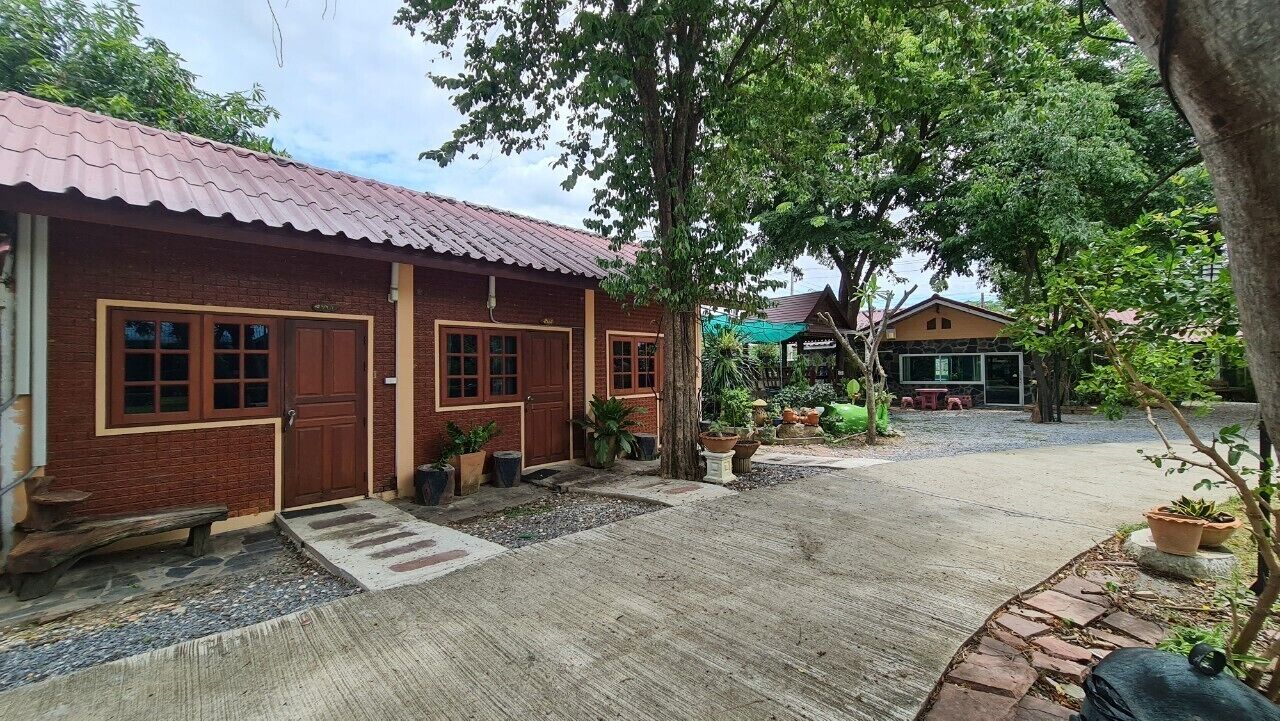 A brick building with a tiled roof, a wooden bench, and potted plants.