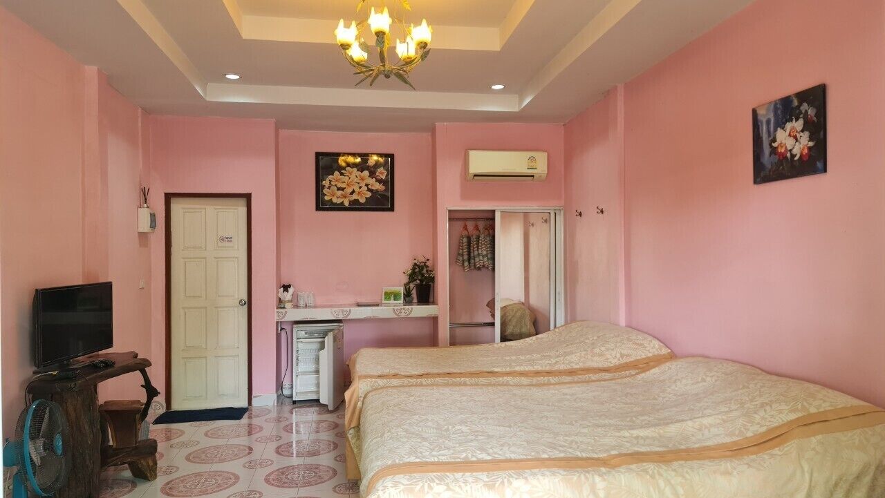 A bedroom with two beds, a desk, a TV, and an air conditioner.