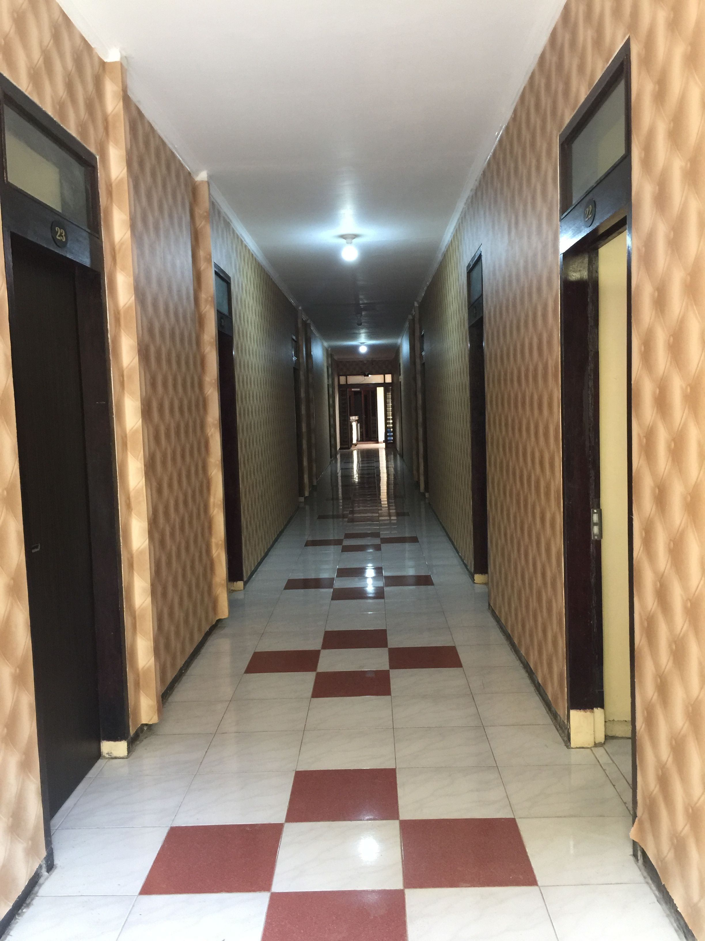 A long, narrow hallway with patterned walls and checkered floor tiles.