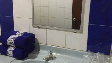 A bathroom sink with a mirror above it, a towel rack with towels, and a small packet on the sink.
