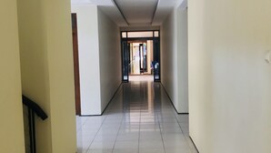 Un long couloir étroit, doté de carreaux au sol et de murs sobres.