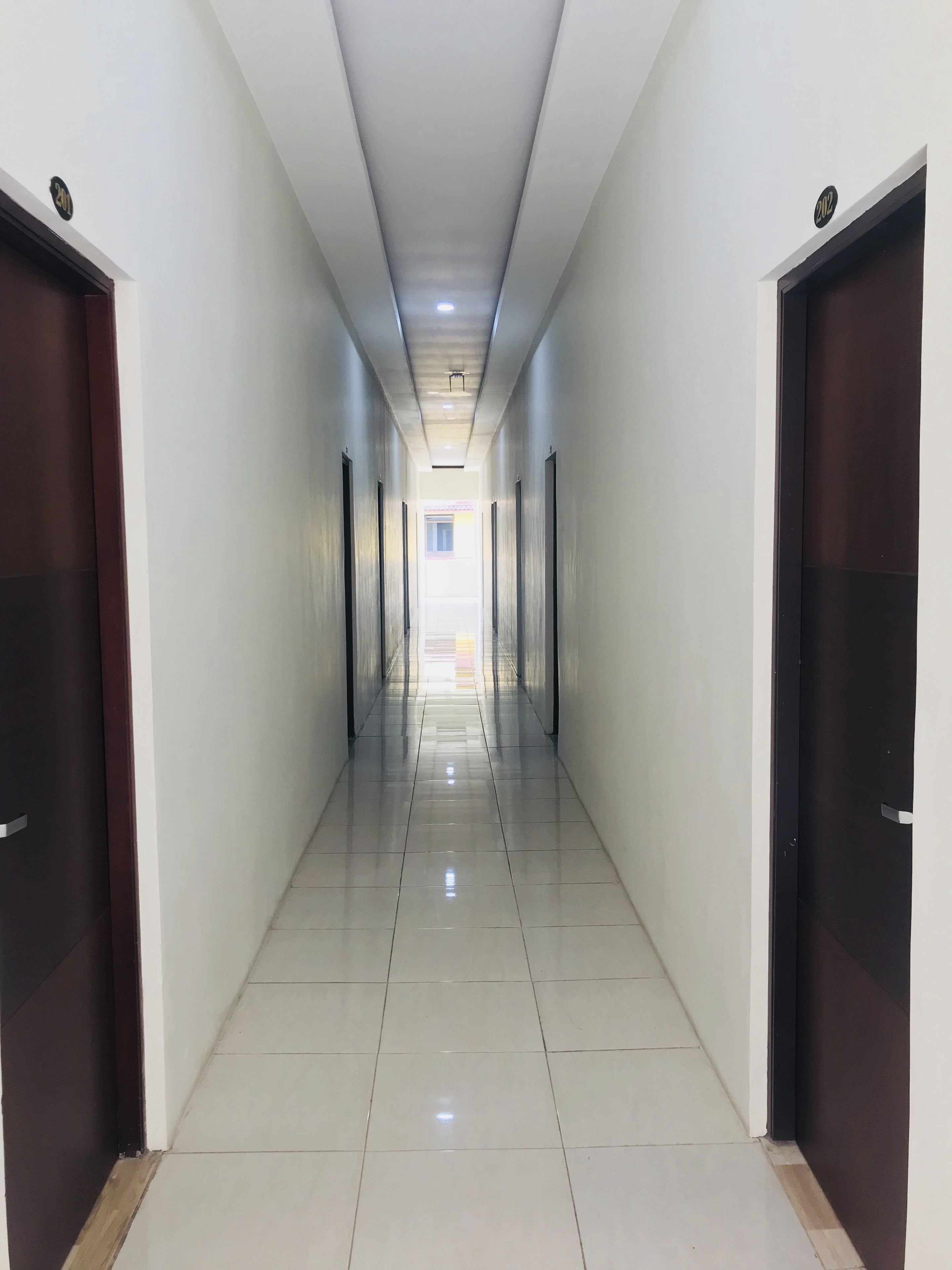 A long, narrow hallway with a tiled floor and doors on both sides.