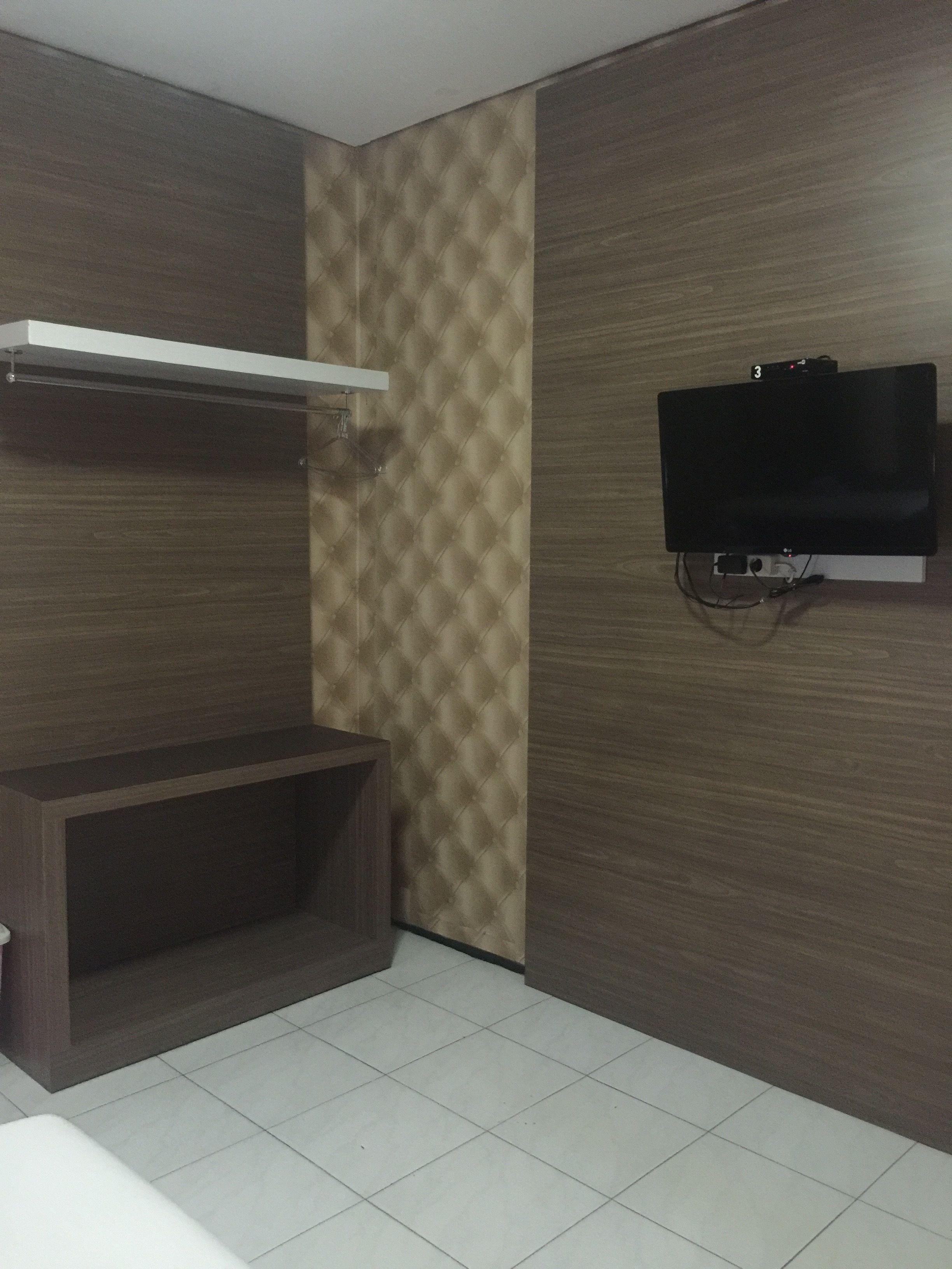 A room with a wooden vanity, a television mounted on the wall, and a tiled floor.