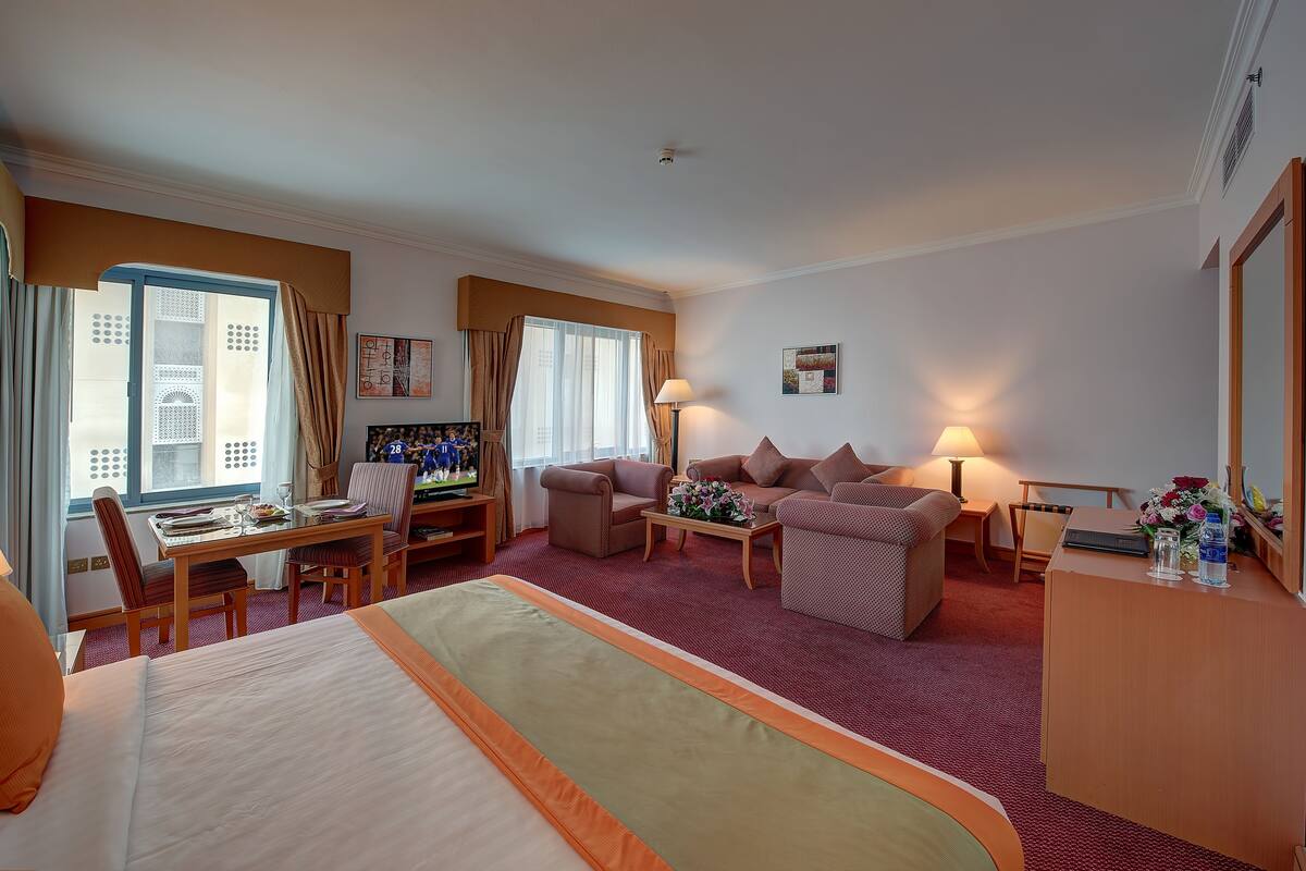 Une chambre d’hôtel comprenant un lit, un bureau avec un ordinateur, un canapé et un coin repas avec des chaises.