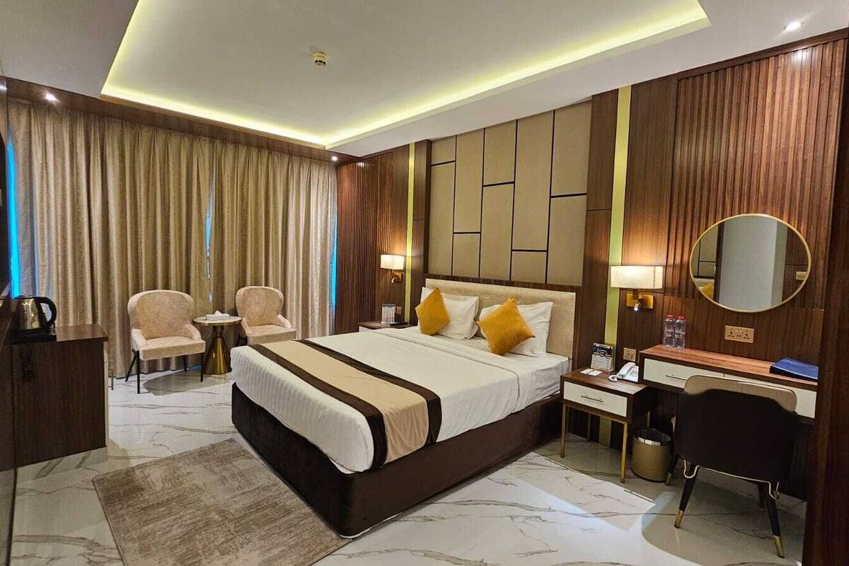 Une chambre d’hôtel avec un grand lit, un bureau, une chaise, un miroir et une télévision.