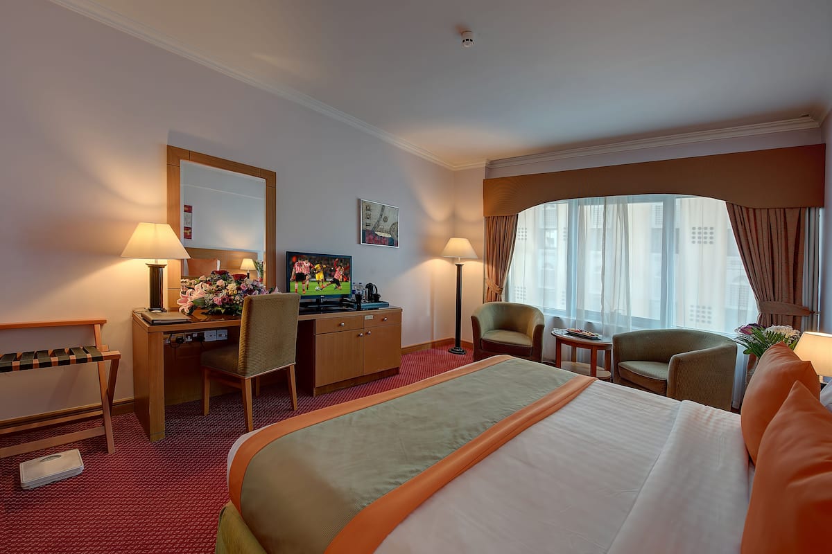 Une chambre d’hôtel avec un lit, un bureau, des chaises et une grande fenêtre.