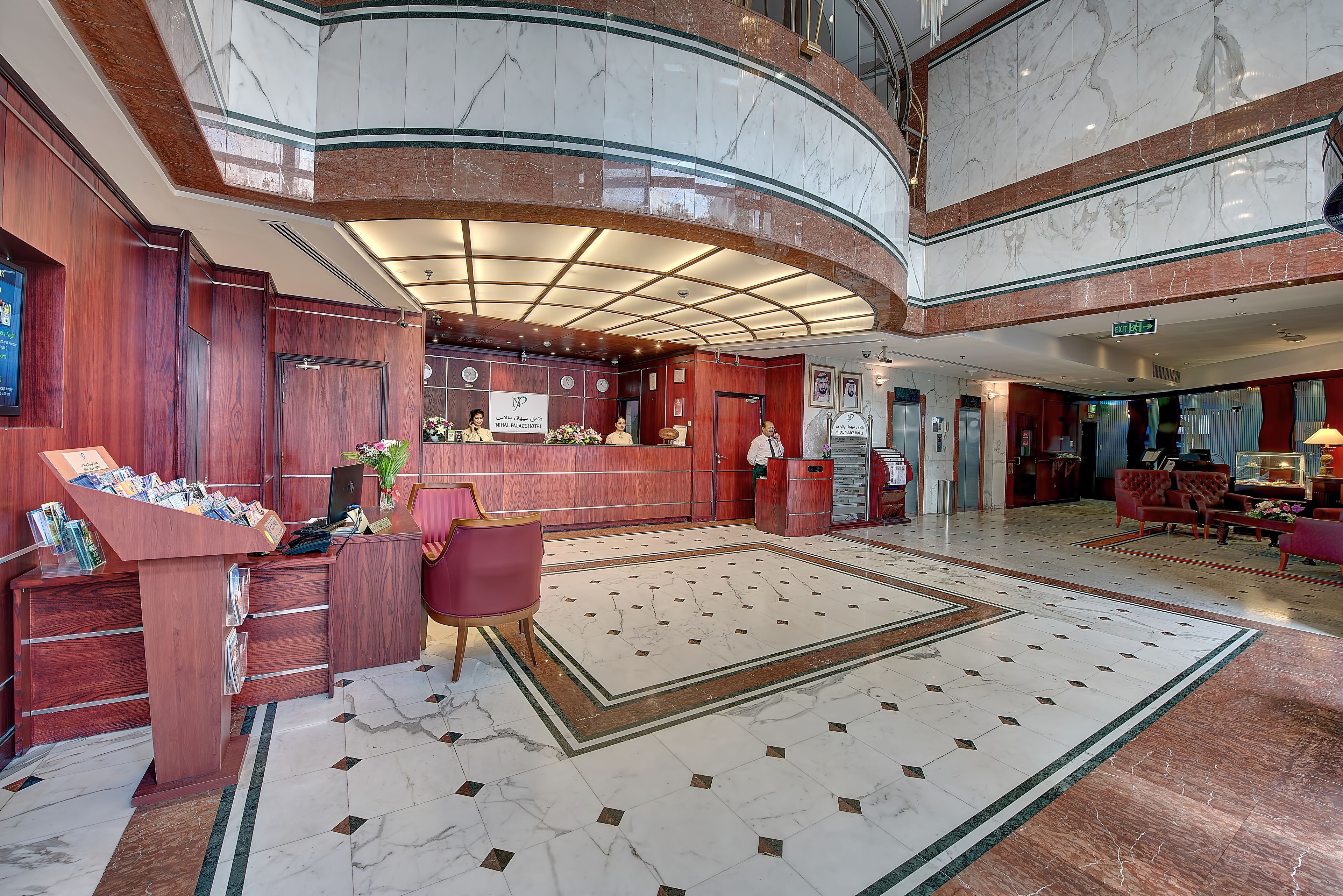 A hotel lobby with a marble reception desk, a red sofa, and a patterned carpet.