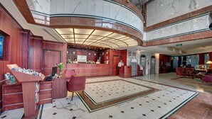 Eine Hotelhalle mit einem Marmor-Empfangstresen, einem roten Sofa und einem gemusterten Teppich.